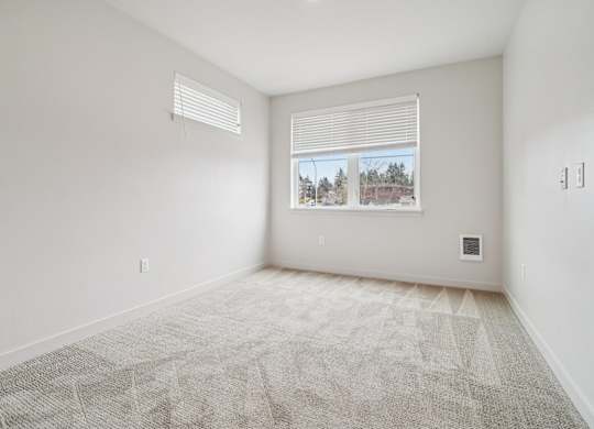 A room with a carpeted floor and a window with blinds.