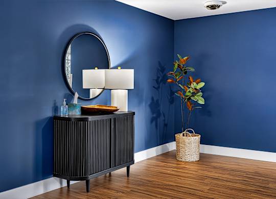 A room with a blue wall and a round mirror.