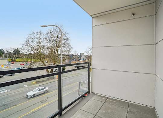 A car is parked on the street below a balcony.