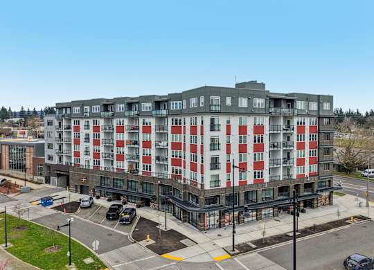 A large building with a red and white facade is surrounded by a parking lot.