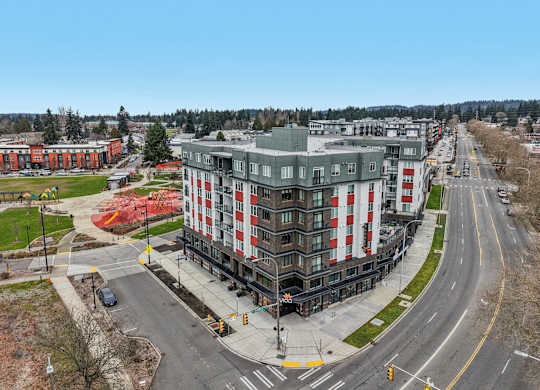 A large building with a curved top is situated on a street corner with a crosswalk in front of it.