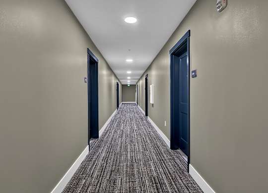 A long hallway with doors on both sides and carpeted flooring.