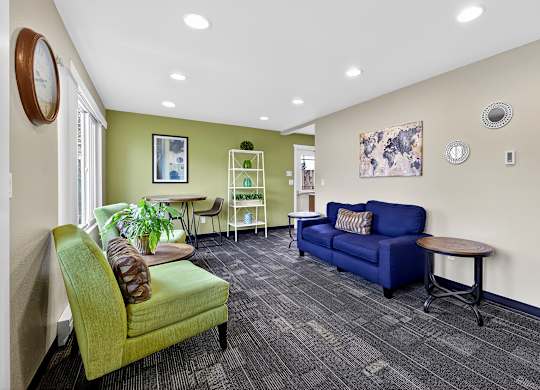 A living room with a green chair and a blue couch.