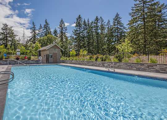 A small building is behind a pool.