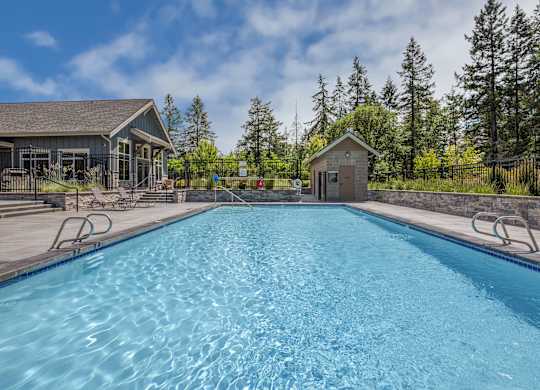 A large blue swimming pool with a small building in the background.
