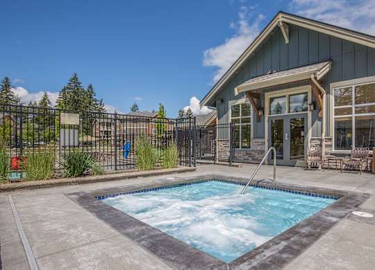 A hot tub sits in the middle of a concrete patio.