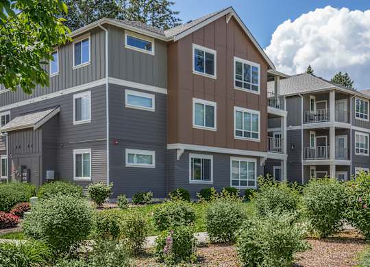A large multi-story residential building with a landscaped front yard.