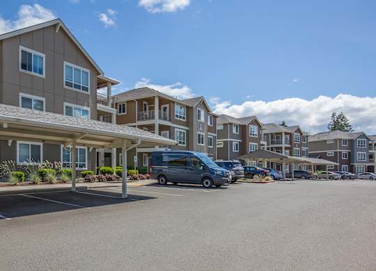 A parking lot in front of apartment buildings with a van parked.