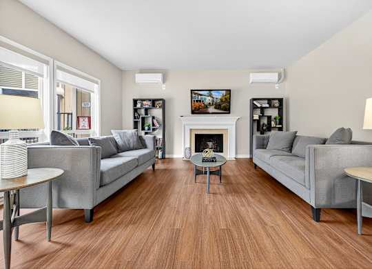 A living room with two grey couches, a coffee table, and a fireplace.