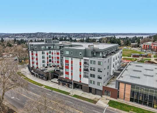 A large multi-story building with a red and white striped facade is surrounded by a parking lot and other buildings.