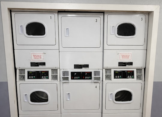 A row of white ovens are lined up against a wall.