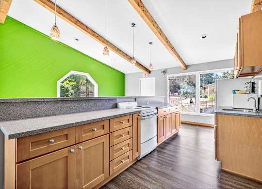 A kitchen with wooden cabinets and a green wall.