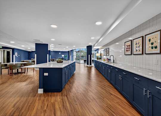 A modern kitchen with dark blue cabinets and a long white island.