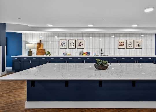 A large white table is in the middle of a room with blue walls and wooden floors.