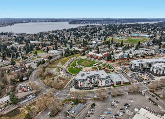A view of a city with a large building in the center and a body of water in the background.