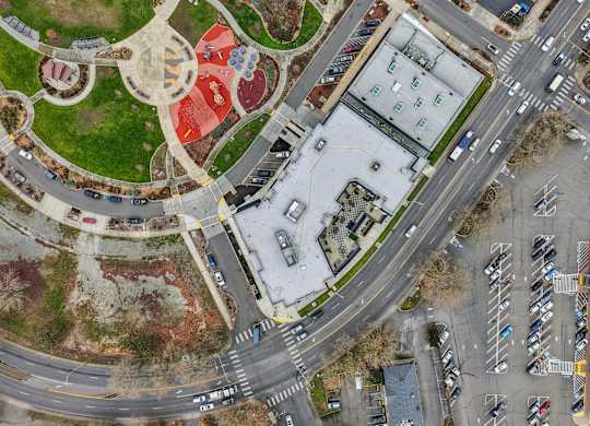 A large roundabout with a red area in the middle and a building with a green roof.