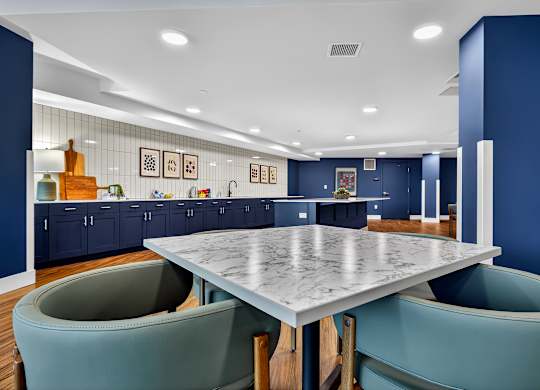 A modern kitchen with a marble table and teal chairs.