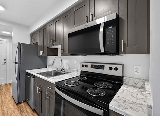 A modern kitchen with a black fridge, microwave, and stove.