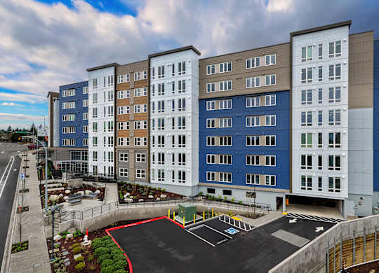 A modern apartment complex with a parking lot in front.