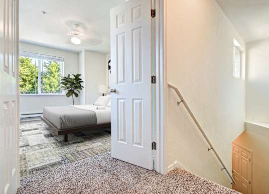 A white door is open in a room with a bed and a plant.