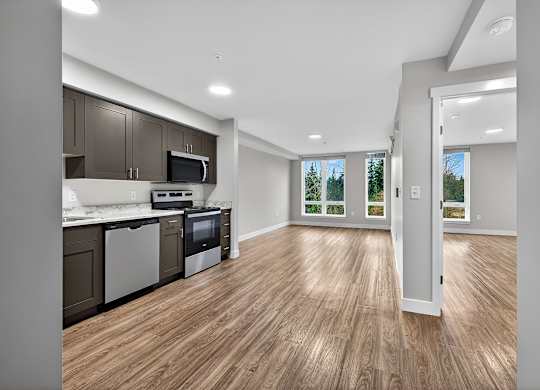 A kitchen with wooden floors and a white door leading to a balcony.