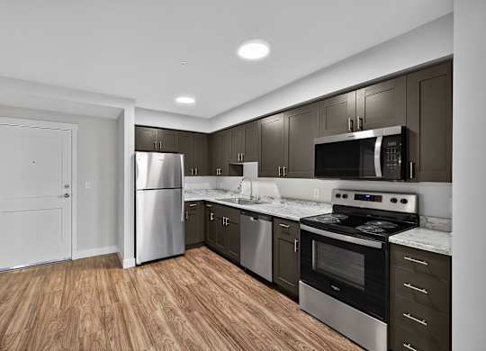 A kitchen with stainless steel appliances and wooden floors.