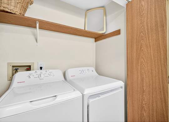 Two white front loading washing machines in a small laundry room.
