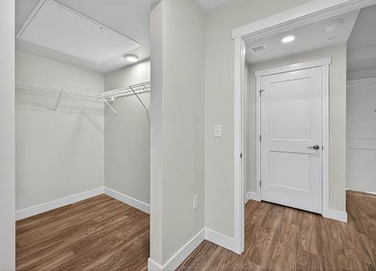 A white door is in a room with wood floors and white walls.