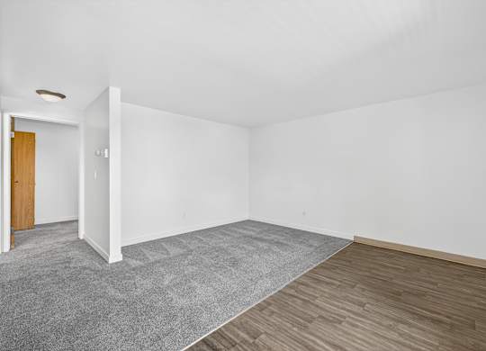A room with a grey carpet and wooden flooring.