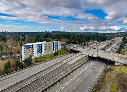A highway interchange with multiple lanes and a large building in the background.