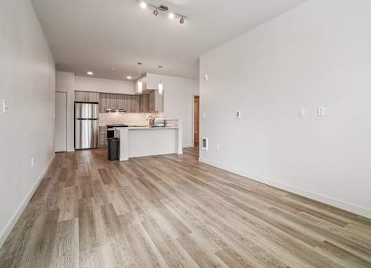 A spacious room with wooden flooring and white walls.