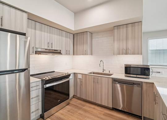 A modern kitchen with a stainless steel refrigerator, microwave, and dishwasher.