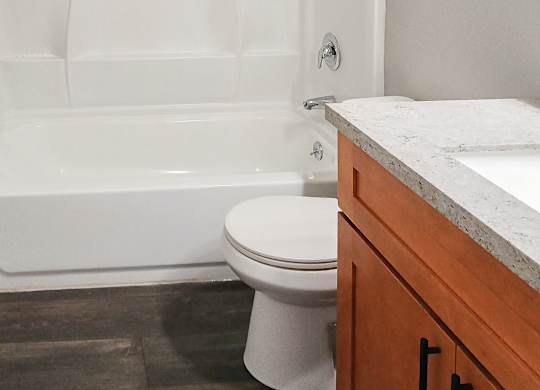 A white toilet sits next to a white bathtub in a bathroom.