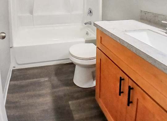 A white toilet sits in a bathroom next to a bathtub and a sink.