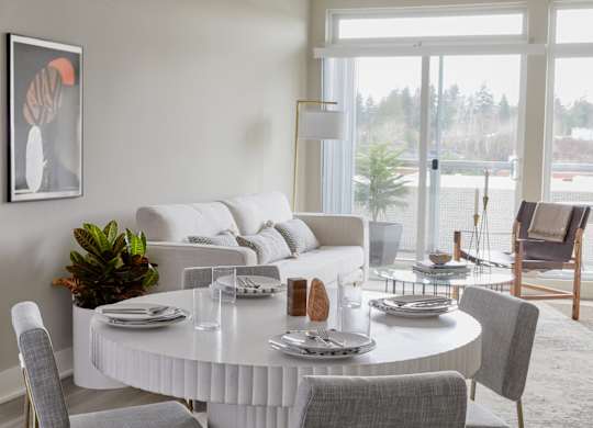 A dining room with a white table and grey chairs.