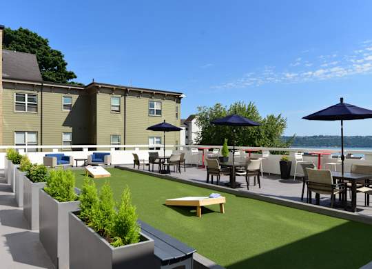 A patio with tables and chairs overlooking a body of water.