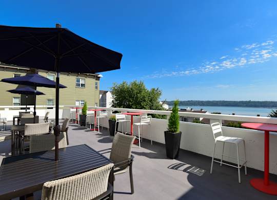 A patio with tables and chairs overlooking a body of water.