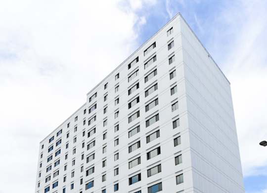 A tall white building with a blue sign on the bottom right.