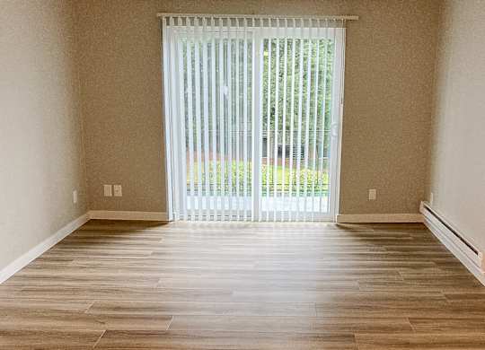 A room with wooden flooring and a sliding glass door.