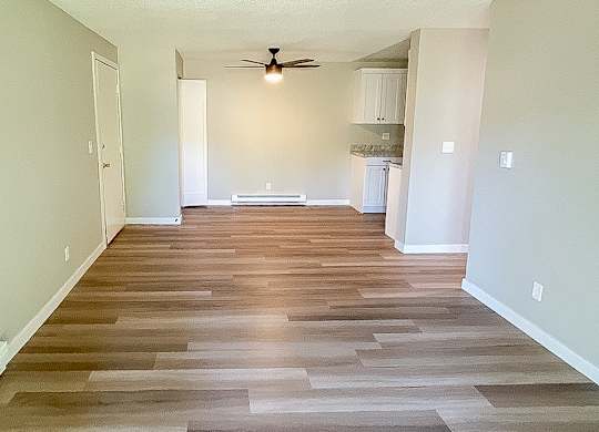 A long hallway with wood flooring and a ceiling fan.