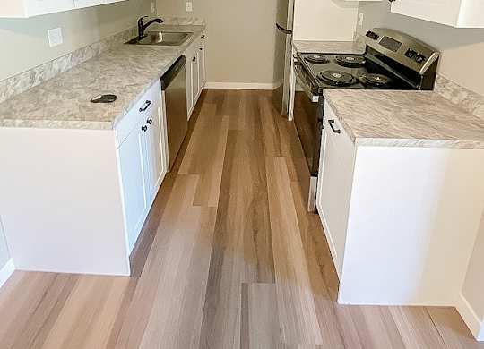 A kitchen with white cabinets and a marble countertop.