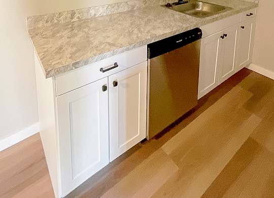 A kitchen with white cabinets and a granite countertop.