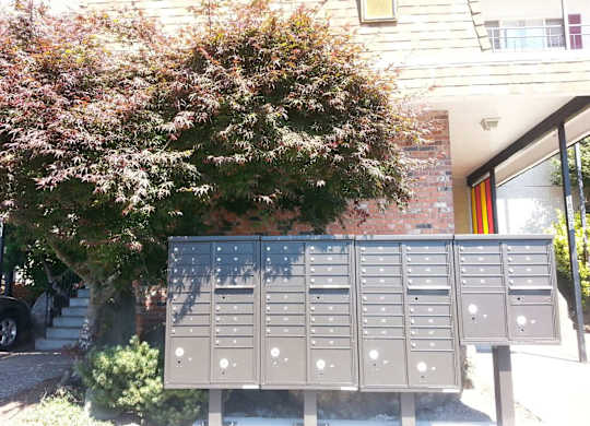 A grey mailbox with a red door in the background.