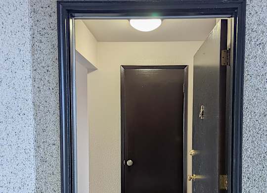 A hallway with a black door and a tiled floor.