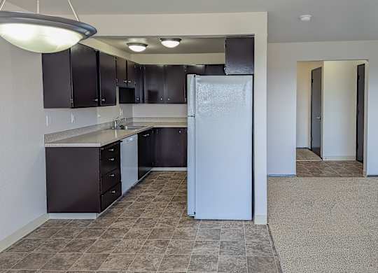 A kitchen with a white refrigerator and brown cabinets.