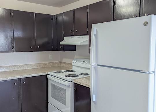 A white refrigerator stands in a kitchen with black cabinets.