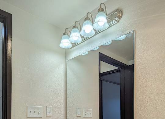 A bathroom with a sink, mirror, and lights.