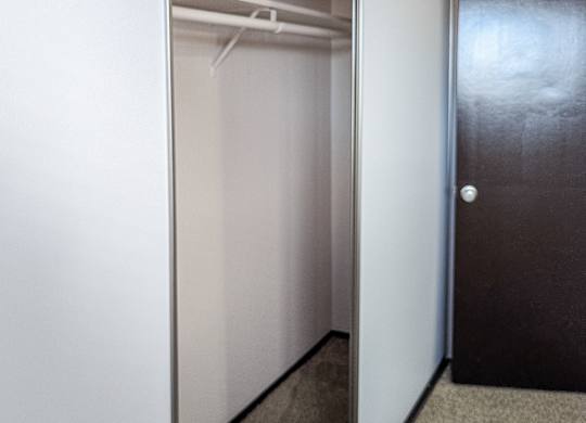 A hallway with a black door and a white wall.