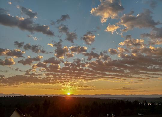 The sun is setting behind the clouds in the sky.