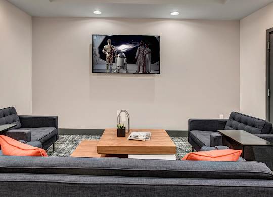 A living room with a grey couch and a painting on the wall.